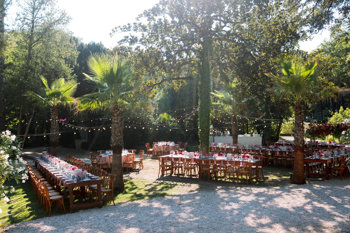 Tables dressées sous les palmiers et les guirlandes lumineuses dans le parc de la Bastide Honorine